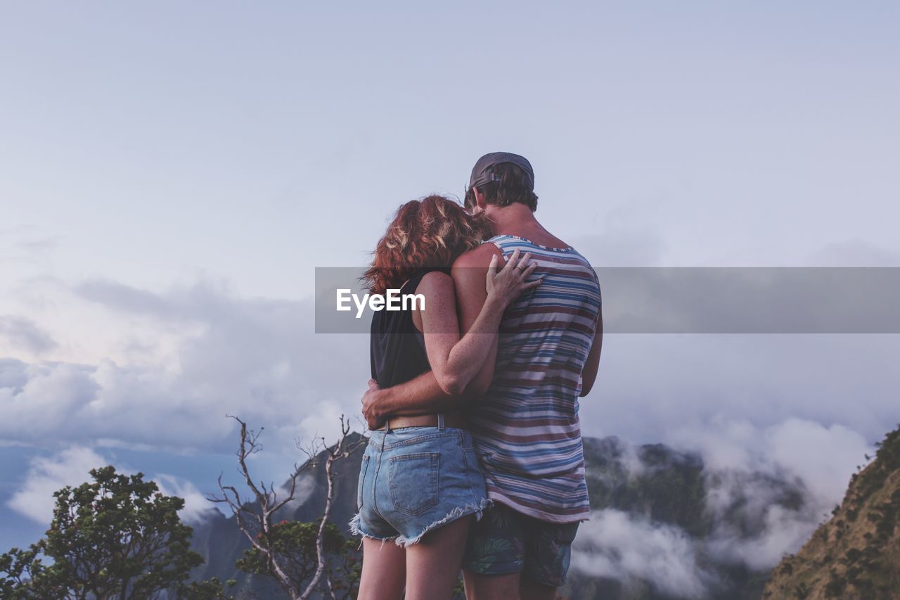 Rear view of couple standing on mountain against sky