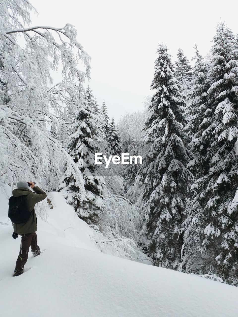 REAR VIEW OF PERSON WALKING ON SNOW COVERED MOUNTAIN