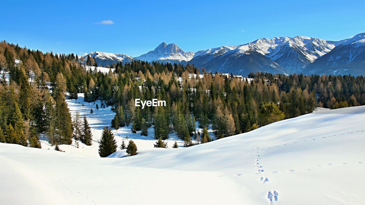 Scenic view of snow covered field and mountains against blue sky