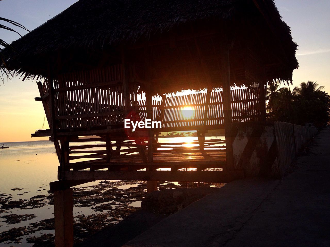 Gazebo by pier at beach during sunset