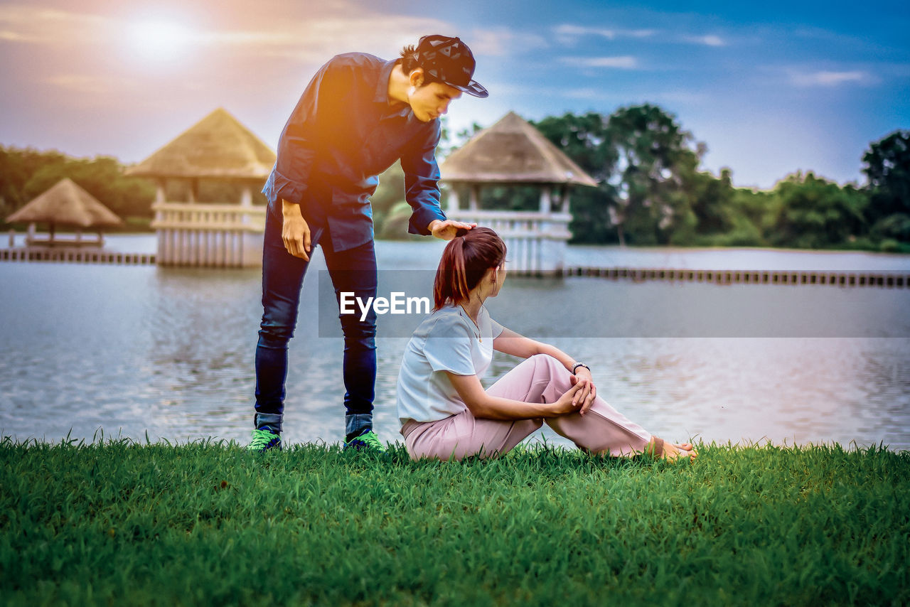 Man and woman by lake against sky