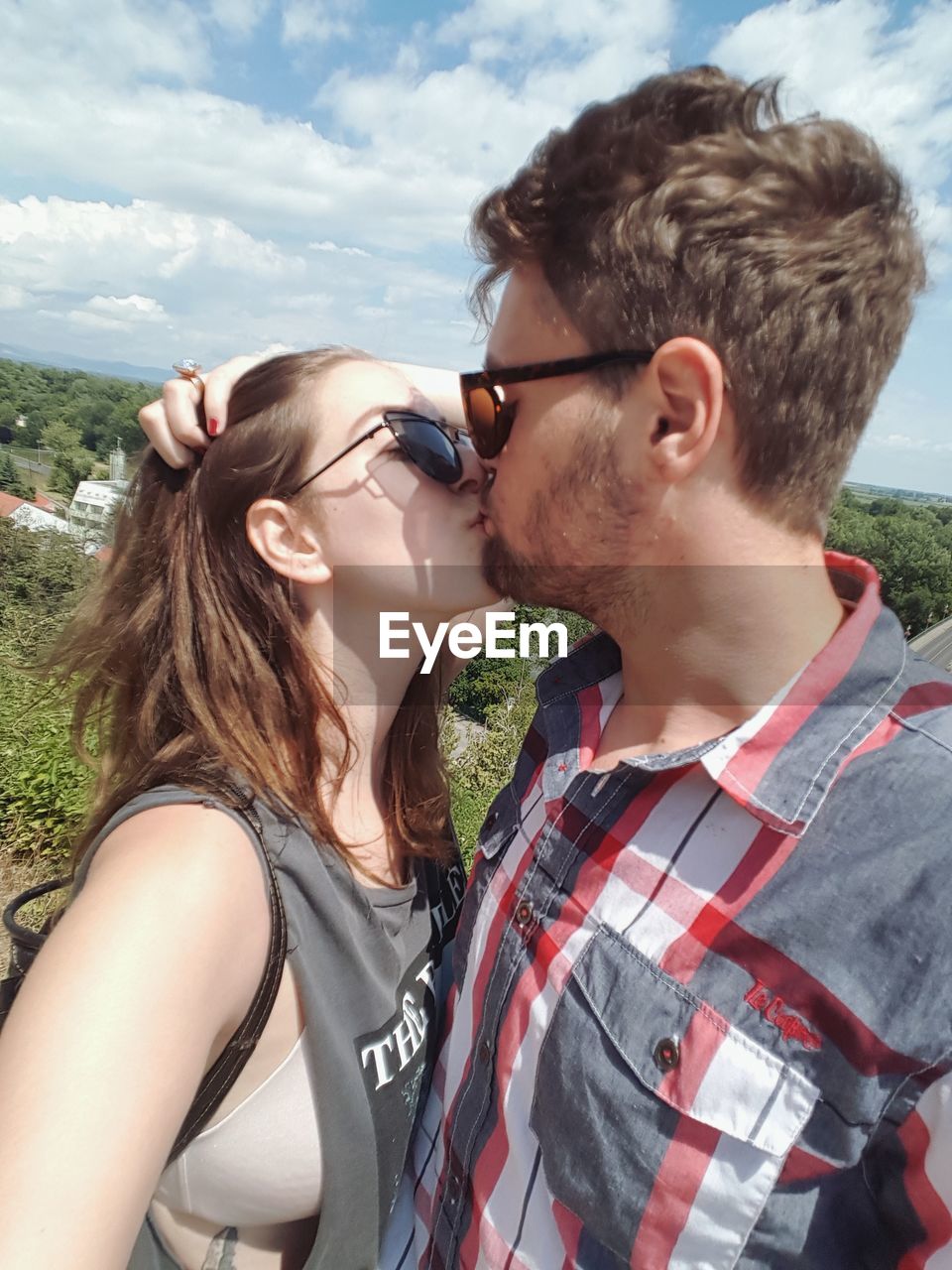 YOUNG COUPLE KISSING AGAINST SKY