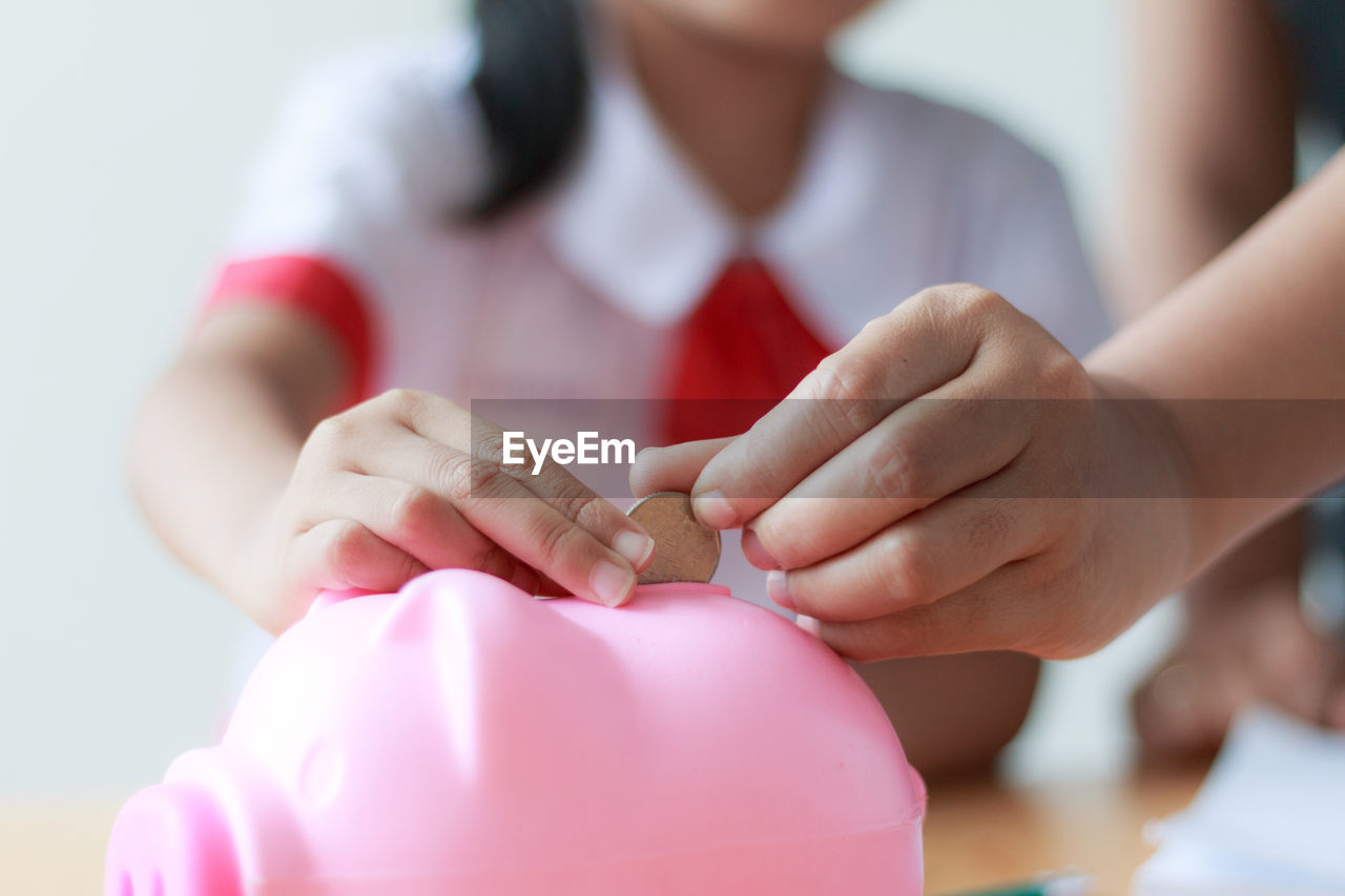 Cropped hand teaching girl to put coin