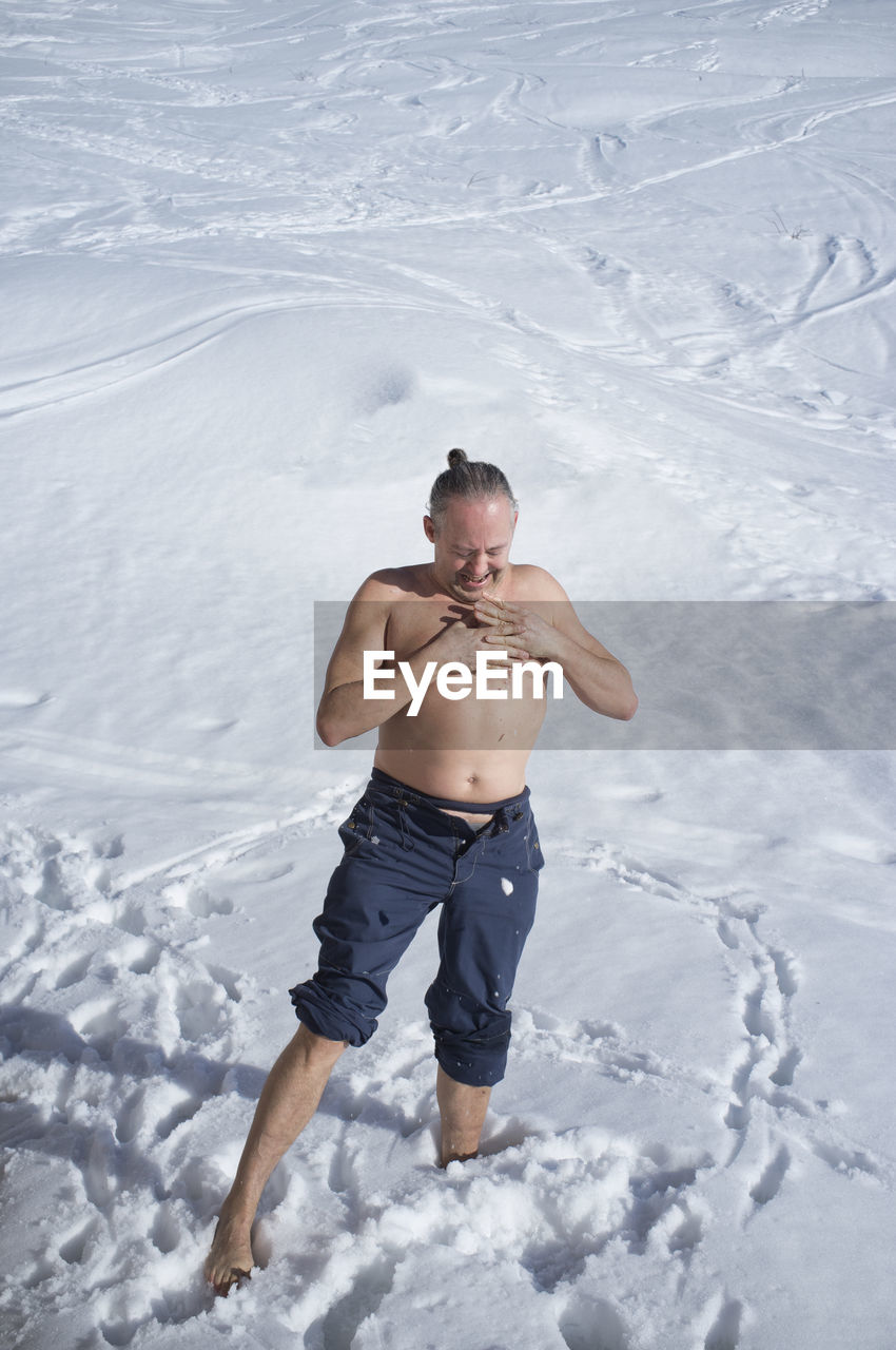 Adult man practicing cryotherapy, in the snow. cryotherapy 