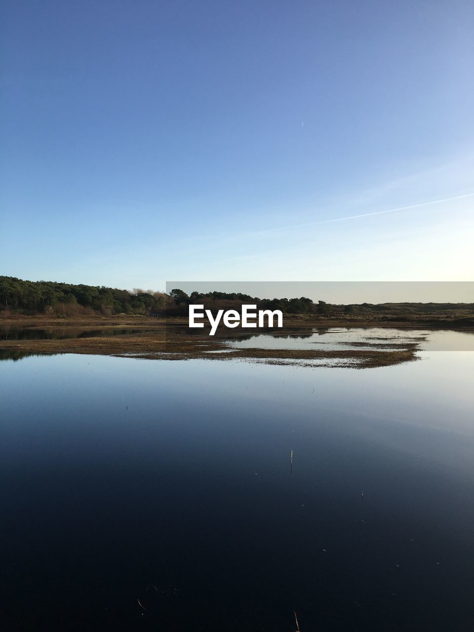 Scenic view of lake against clear blue sky