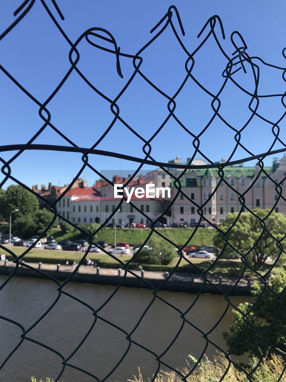 CITY SEEN THROUGH CHAINLINK FENCE AGAINST SKY DURING AUTUMN