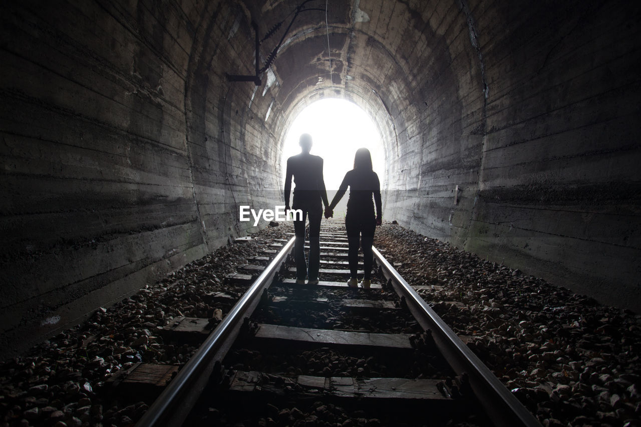 REAR VIEW OF SILHOUETTE PEOPLE IN TUNNEL