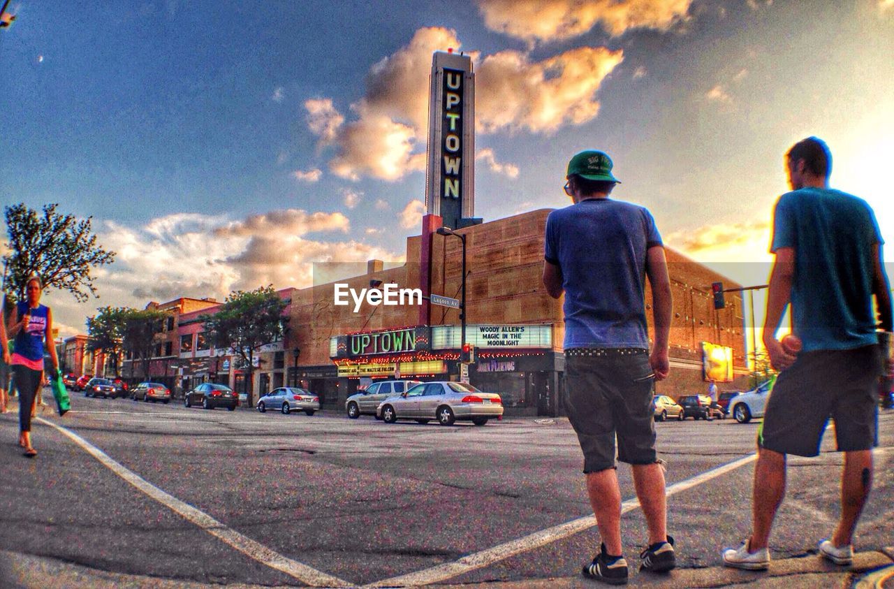 MAN STANDING ON CITY STREET AGAINST SKY