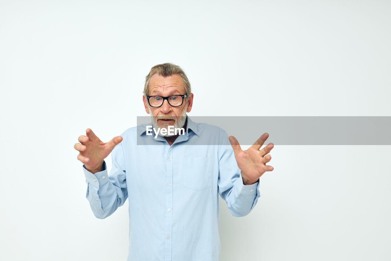 Portrait of senior man standing against white background