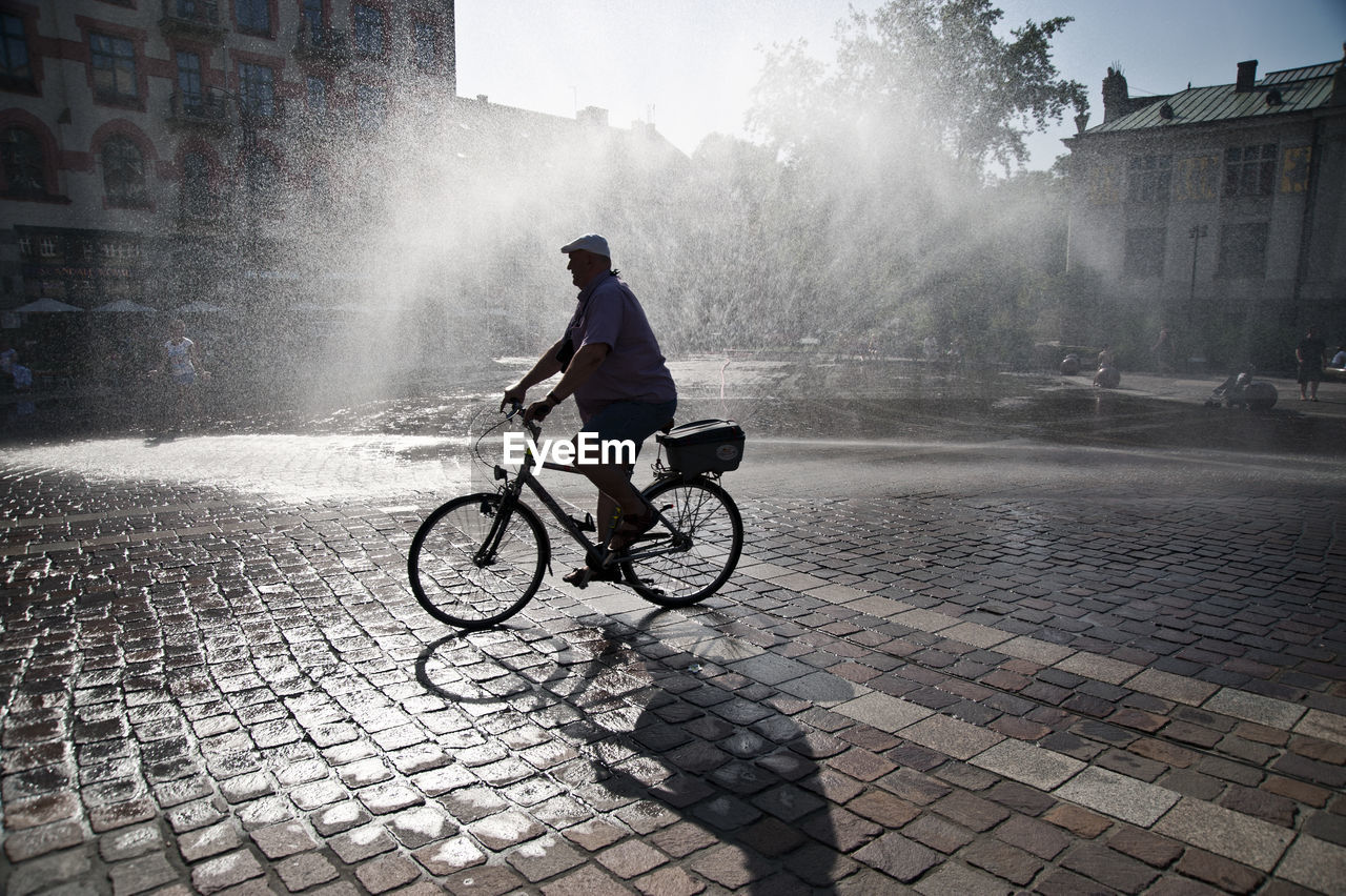 FULL LENGTH OF MAN RIDING BICYCLE ON STREET