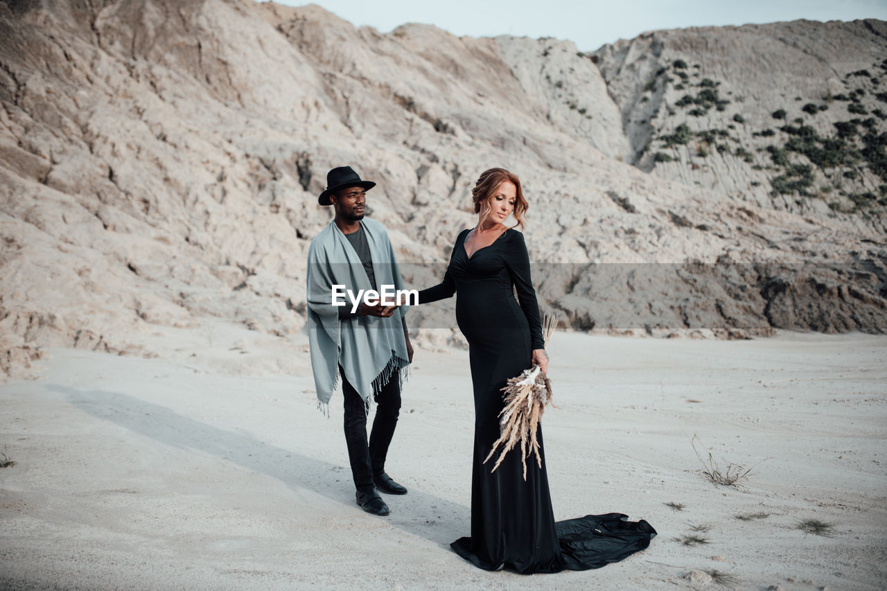 Full length of couple standing on sand in desert