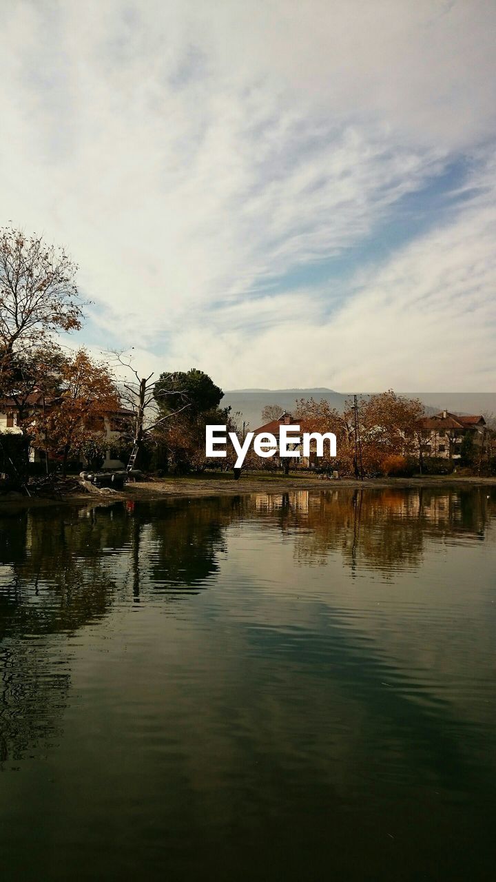 Houses by lake against sky