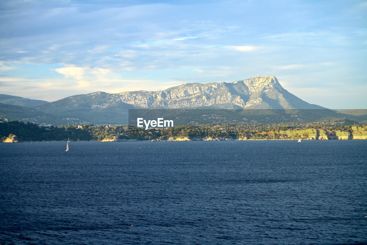 Scenic view of sea by snowcapped mountain against sky