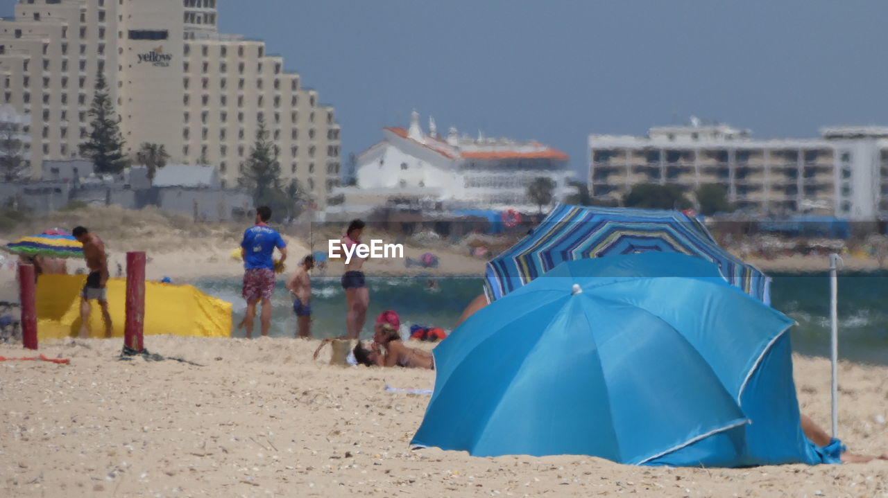 PEOPLE ON BEACH WITH CITY IN BACKGROUND