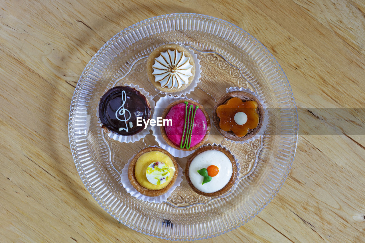 table, food and drink, food, high angle view, directly above, plate, sweet food, freshness, indoors, still life, wood, no people, sweet, dessert, cake, baked, circle, close-up, healthy eating, art, shape, temptation, multi colored