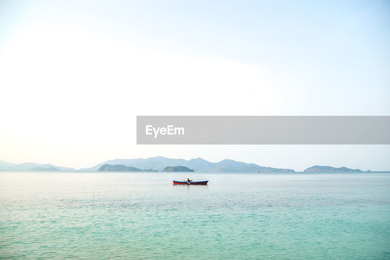 Man boating in sea against sky