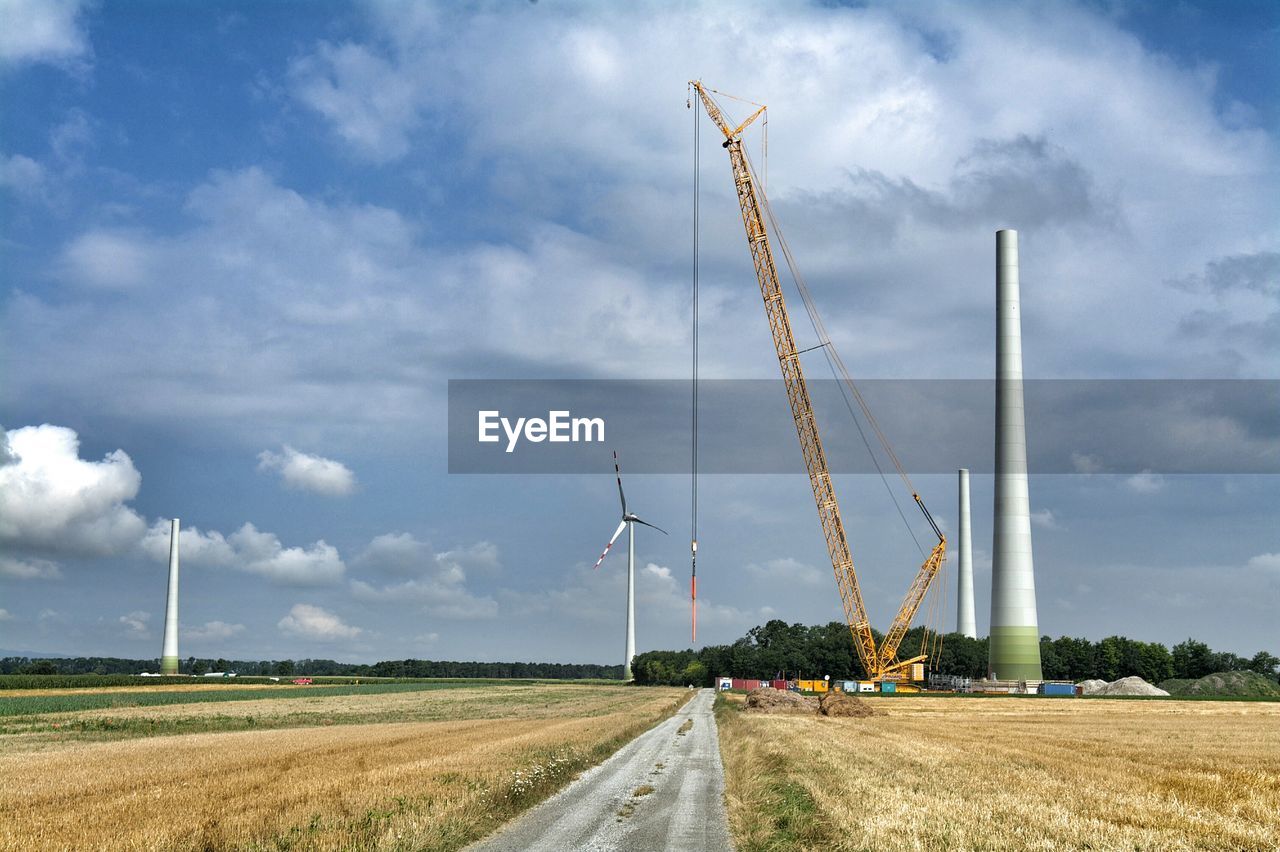 Scenic view of wind turbine against cloudy sky