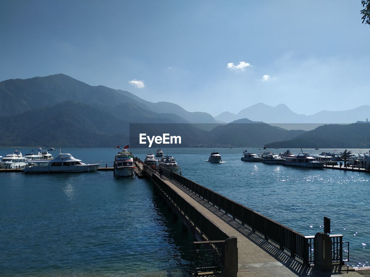 Scenic view of harbor by mountains against sky