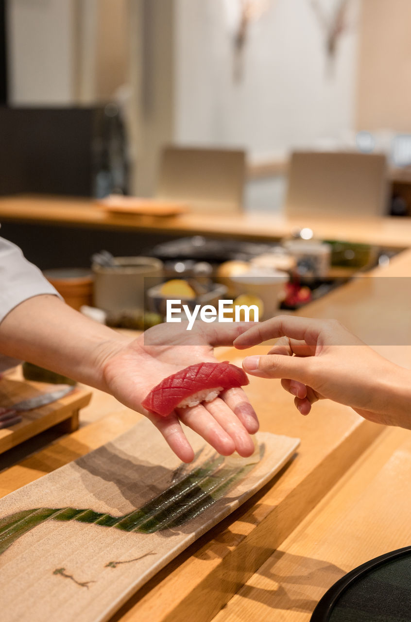 Customer receiving sushi from chef