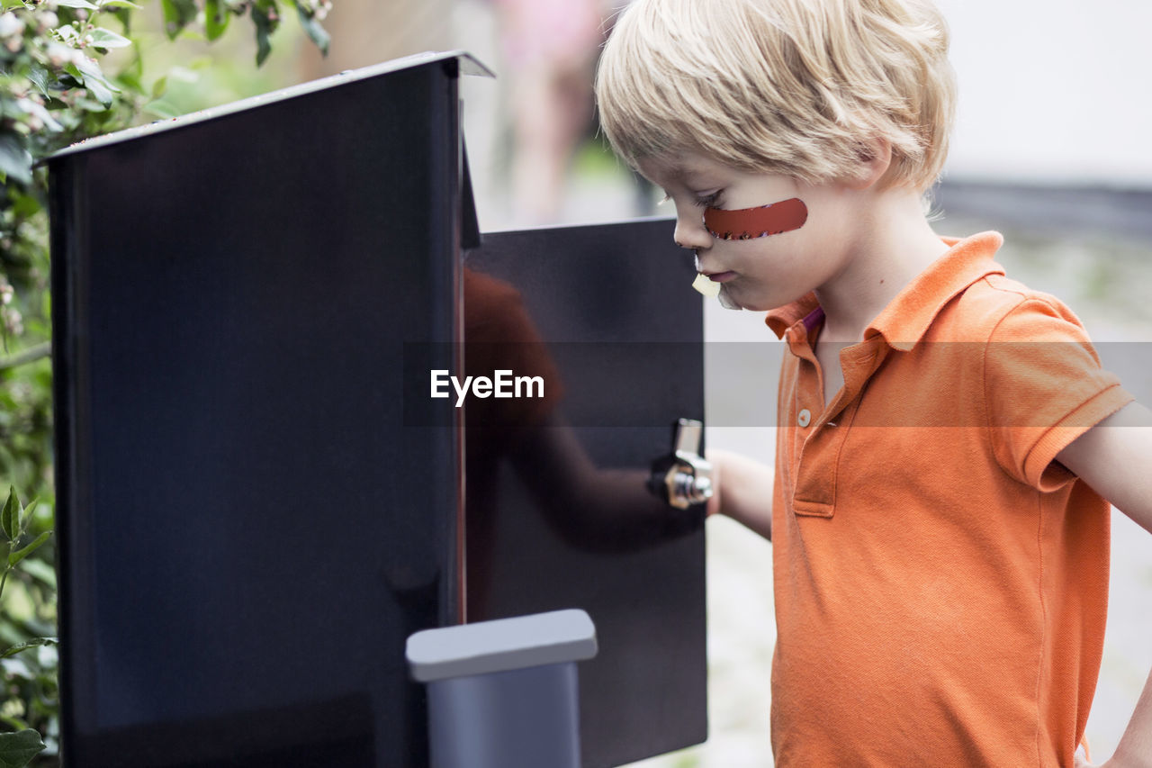 Boy looking into letter box outdoors