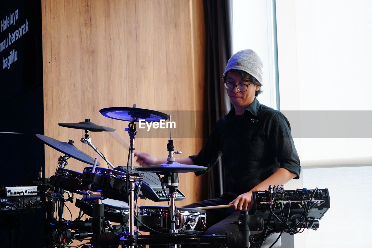 Portrait of a young man drummer play a drum