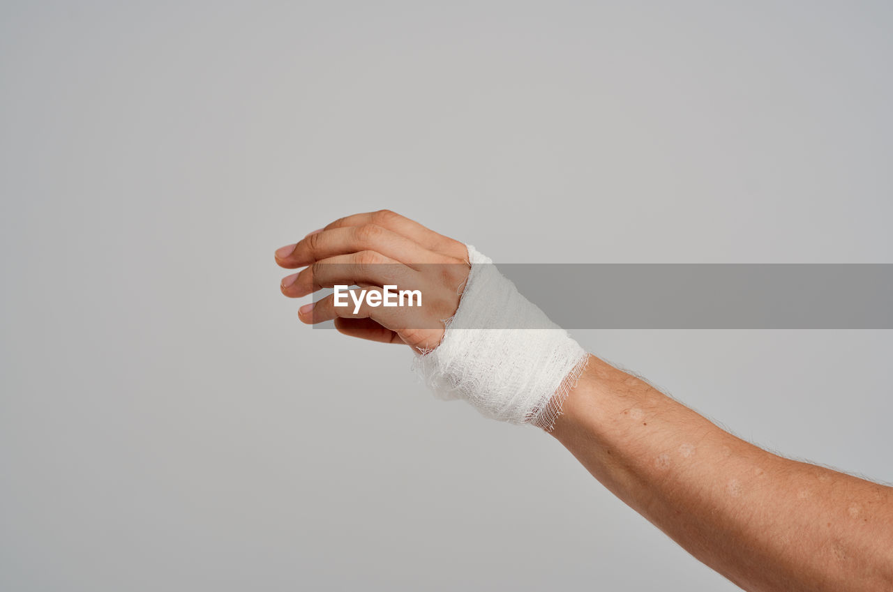 CLOSE-UP OF MAN HAND AGAINST WHITE BACKGROUND