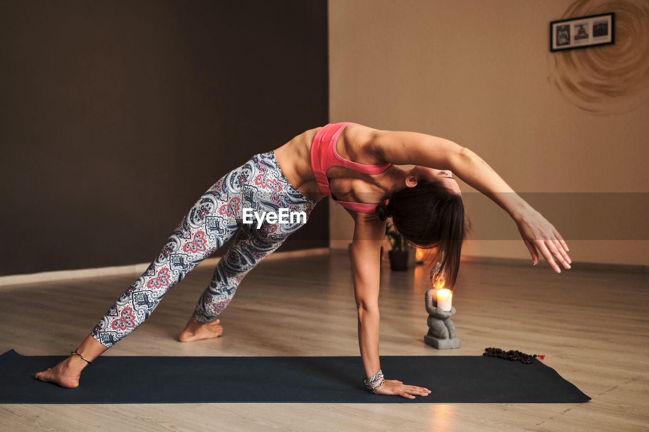 Young woman doing yoga on yoga mat in atmospheric yoga studio