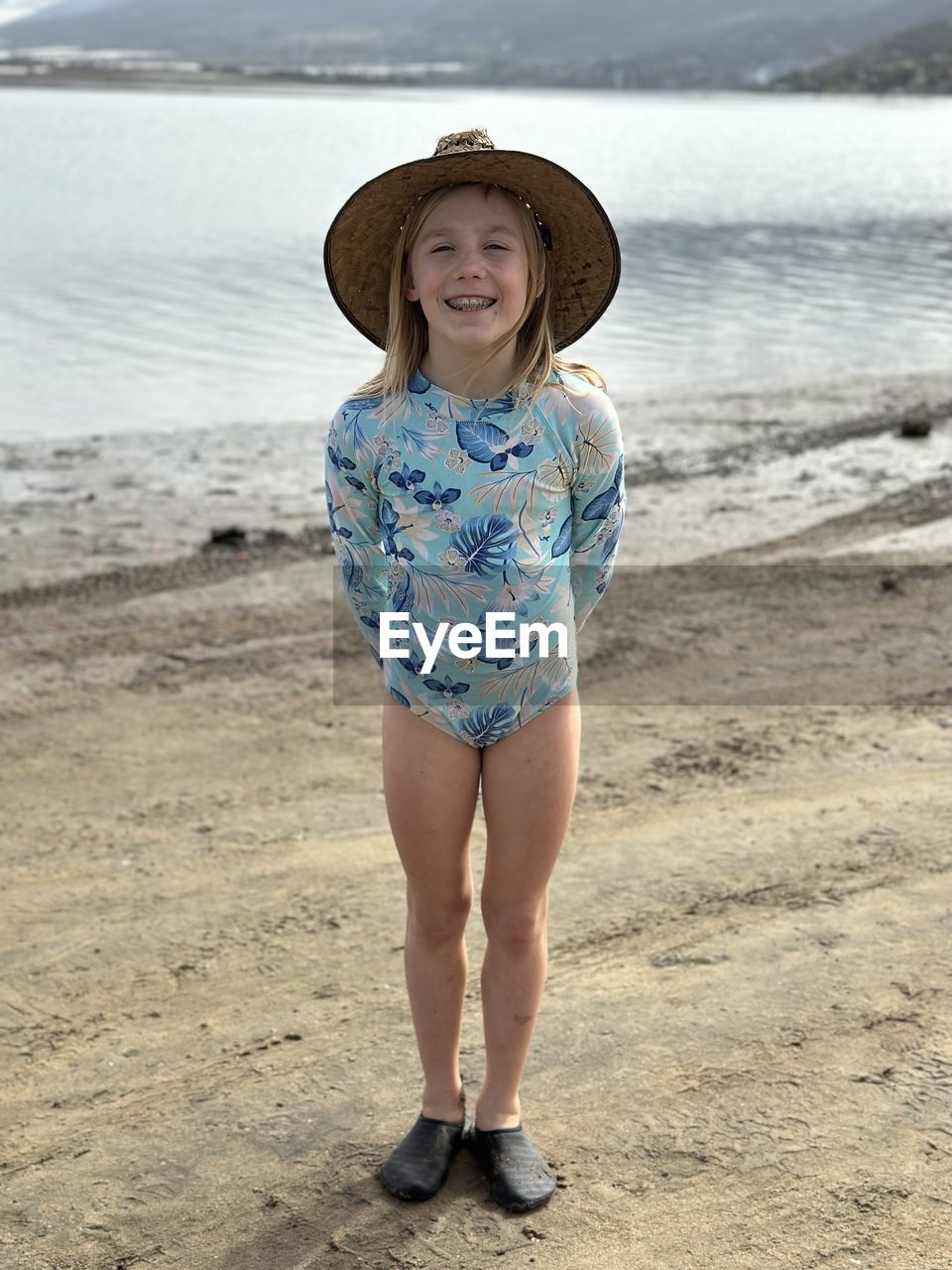 portrait of young woman wearing hat standing at beach