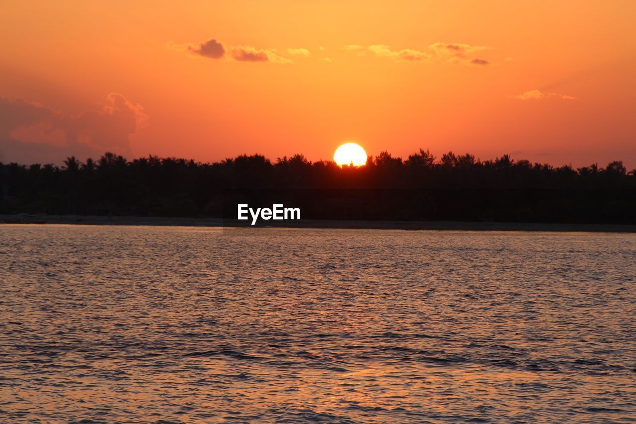 Scenic view of lake against sky at sunset