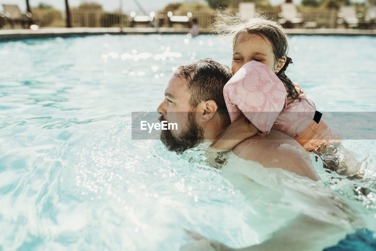 Father and daughter swimming together in a pool on california vacation