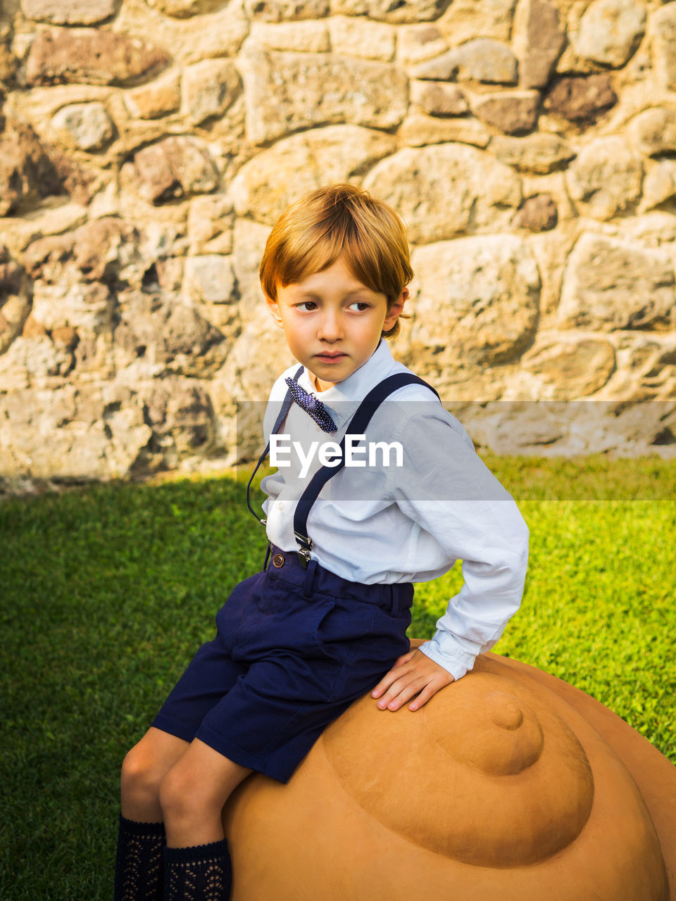 Boy looking away while sitting at park