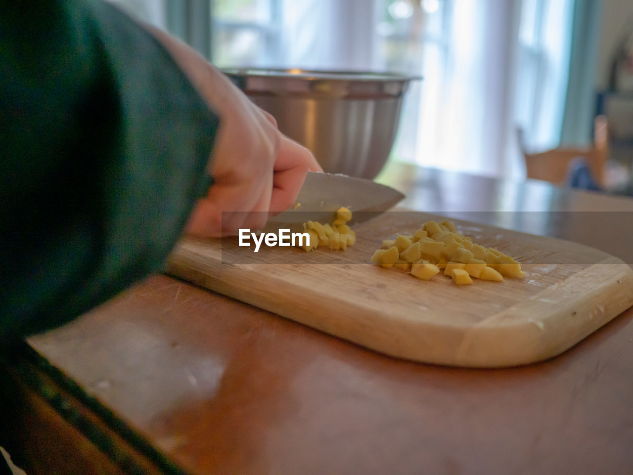 Cropped hands of person cutting food on board at home