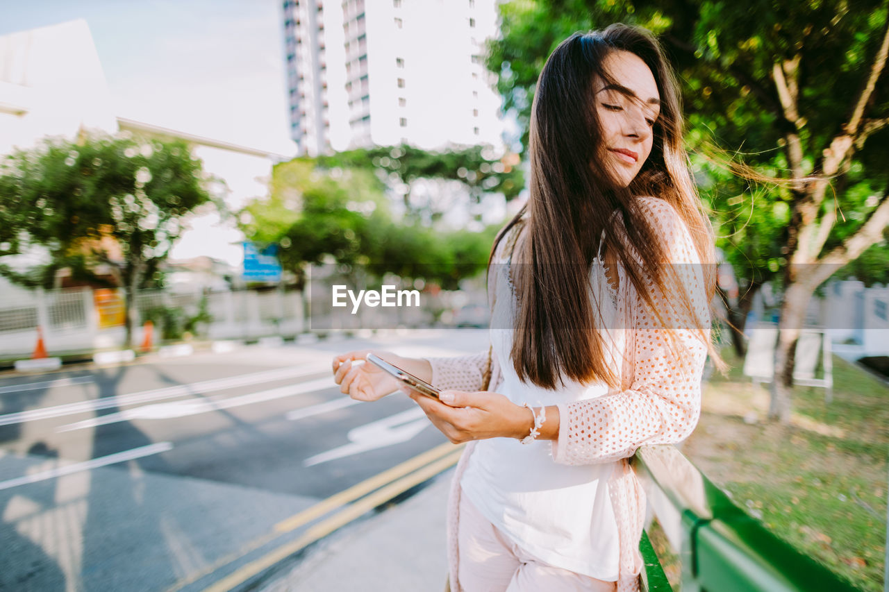 YOUNG WOMAN USING PHONE IN CITY