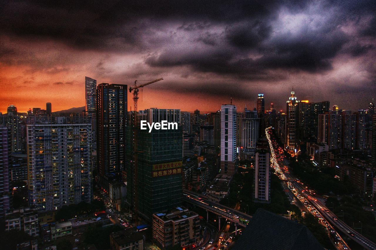 VIEW OF ILLUMINATED CITYSCAPE AGAINST CLOUDY SKY