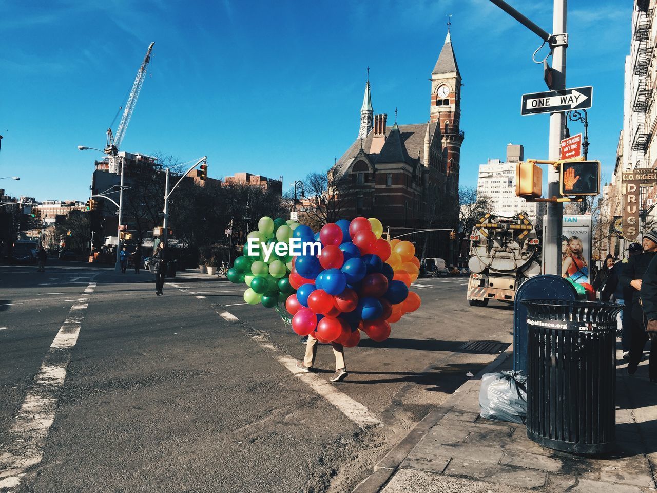 Man carrying bunch of colorful balloons on street