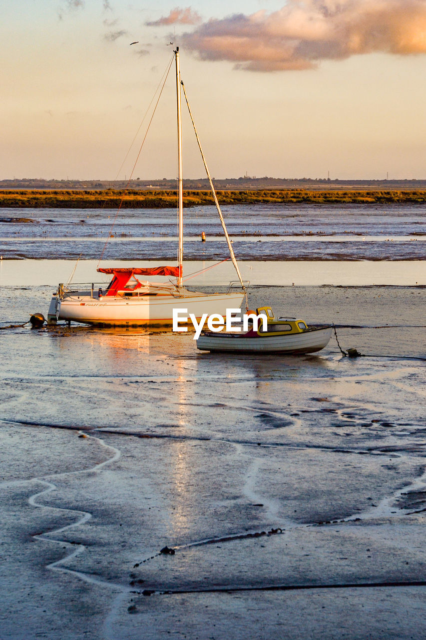 Boat moored on sea against sky during sunset