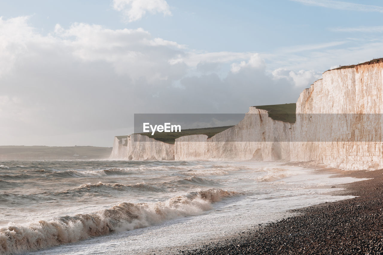 Waves hitting the pebble beach by seven sisters chalk cliffs in east sussex, uk.