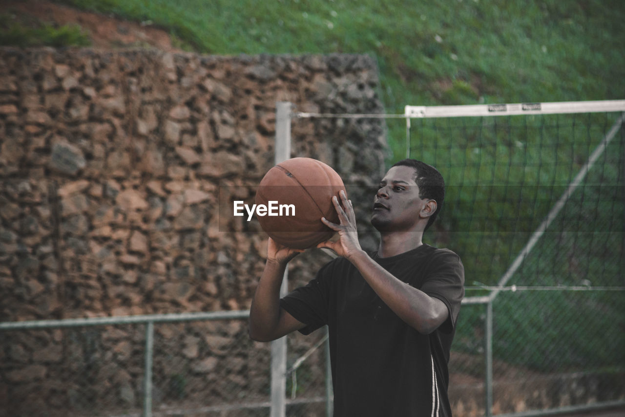 Young man playing basket ball at court