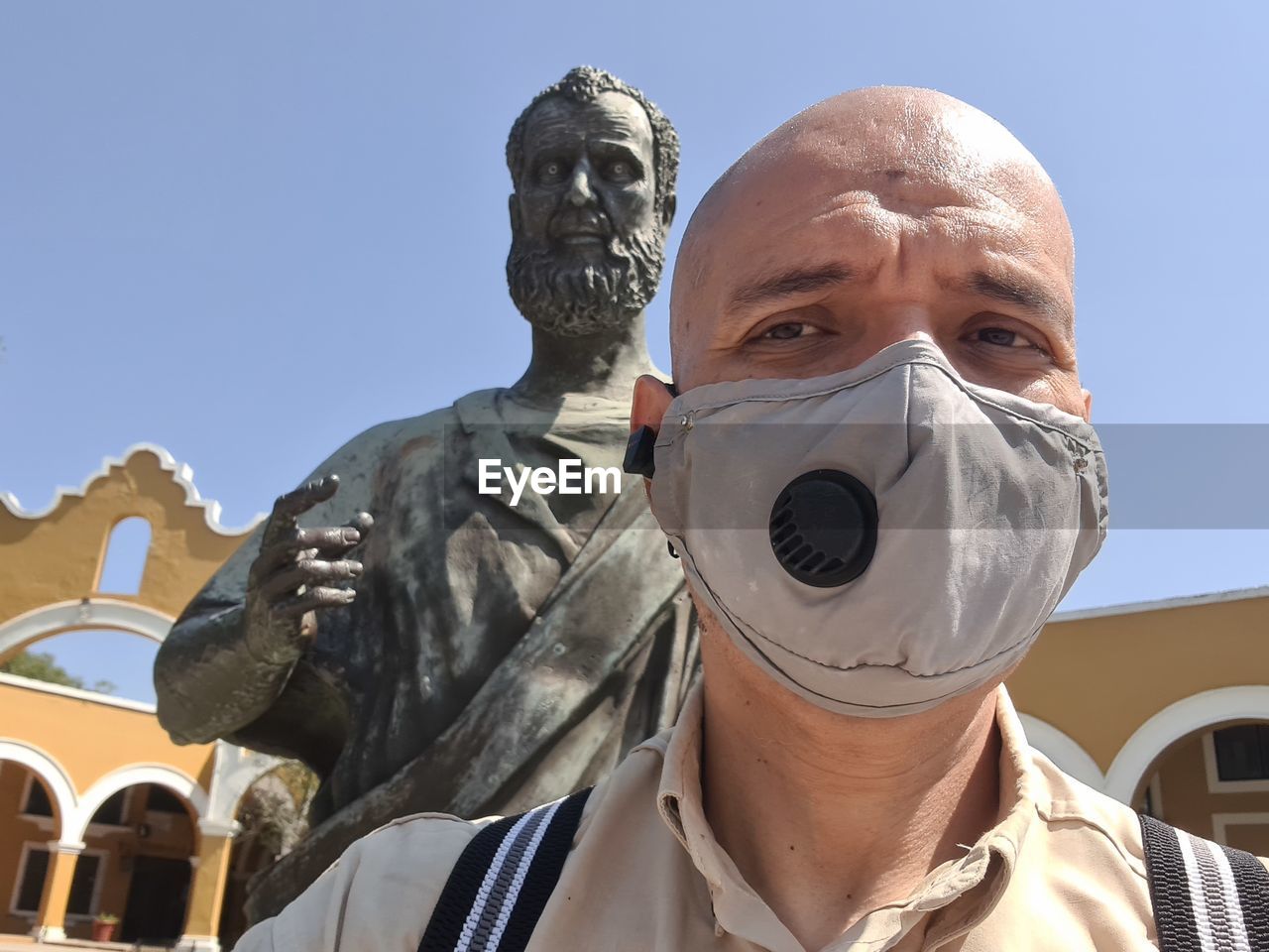 PORTRAIT OF MAN AGAINST STATUE AGAINST CLEAR SKY