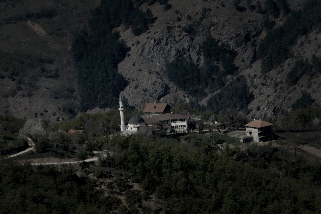 Houses and mosque on landscape against hill