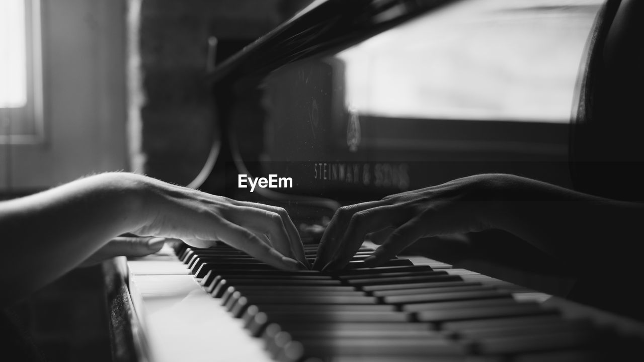 MIDSECTION OF PERSON PLAYING PIANO AT HOME