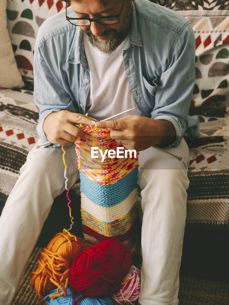 midsection of man sitting on bed