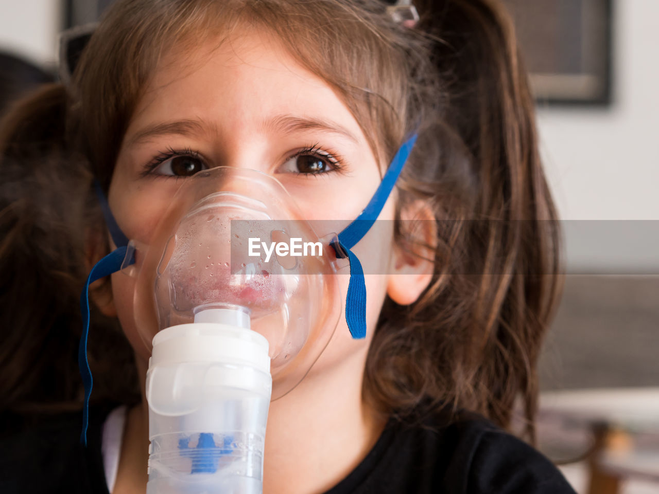 Cute girl wearing oxygen mask in clinic