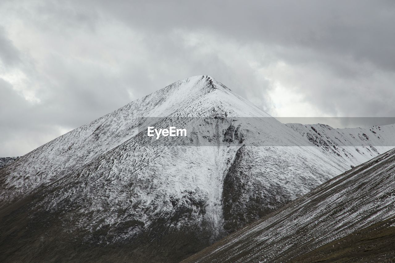 Scenic view of snow covered mountains against cloudy sky