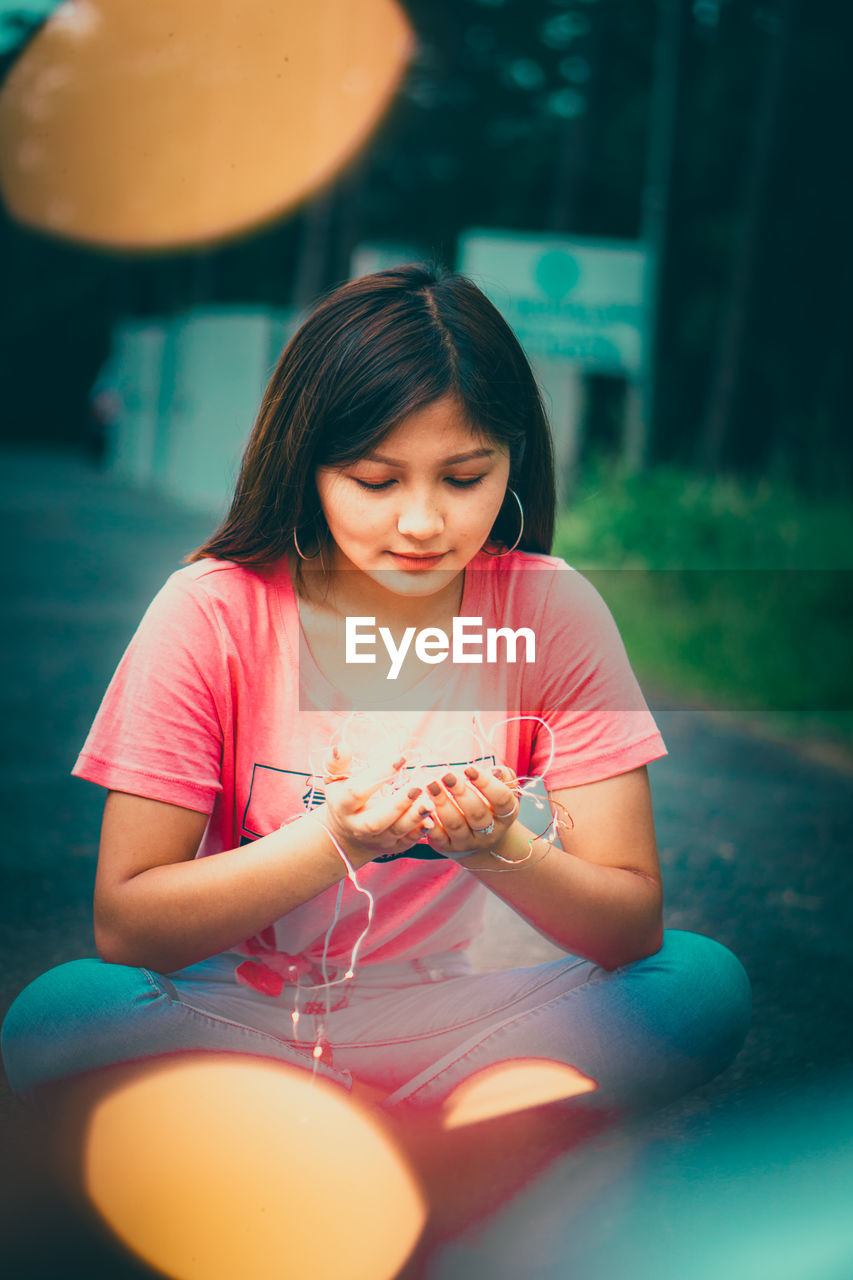 YOUNG WOMAN LOOKING AWAY WHILE SITTING IN PINK