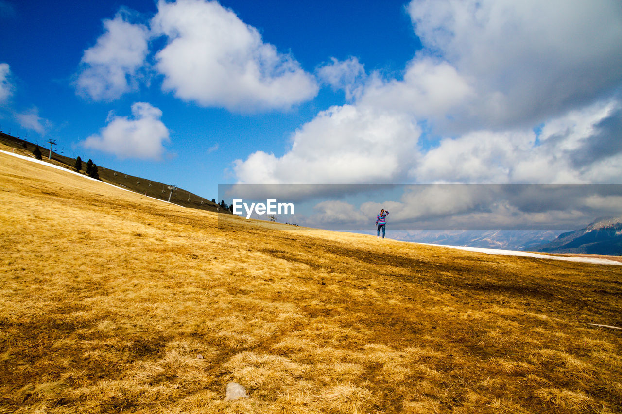 Man walking on field against sky