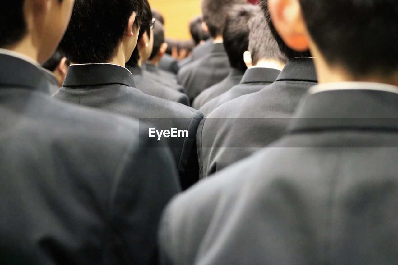 Rear view of young men in suits at ceremony 