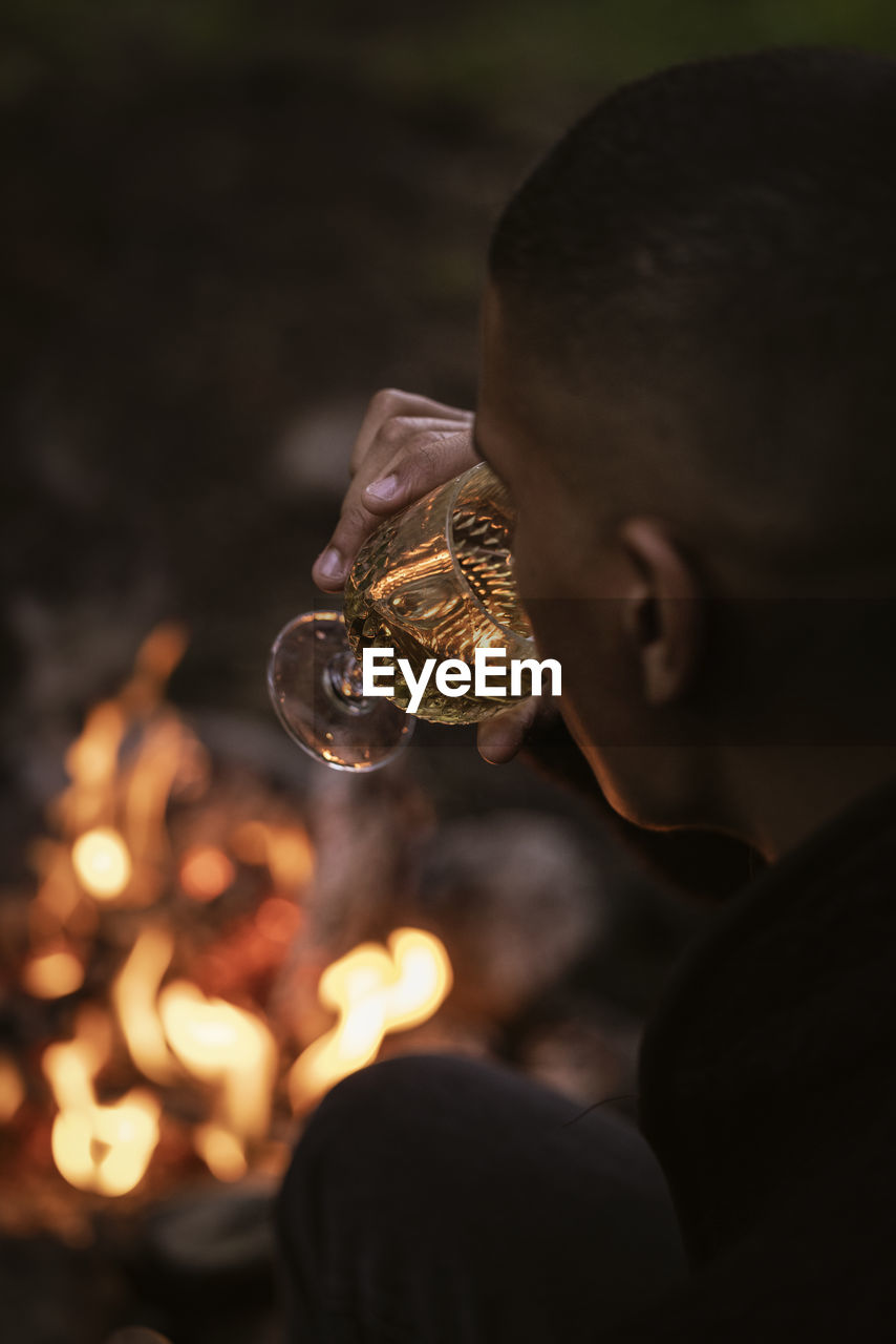 Man drinking wine by campfire