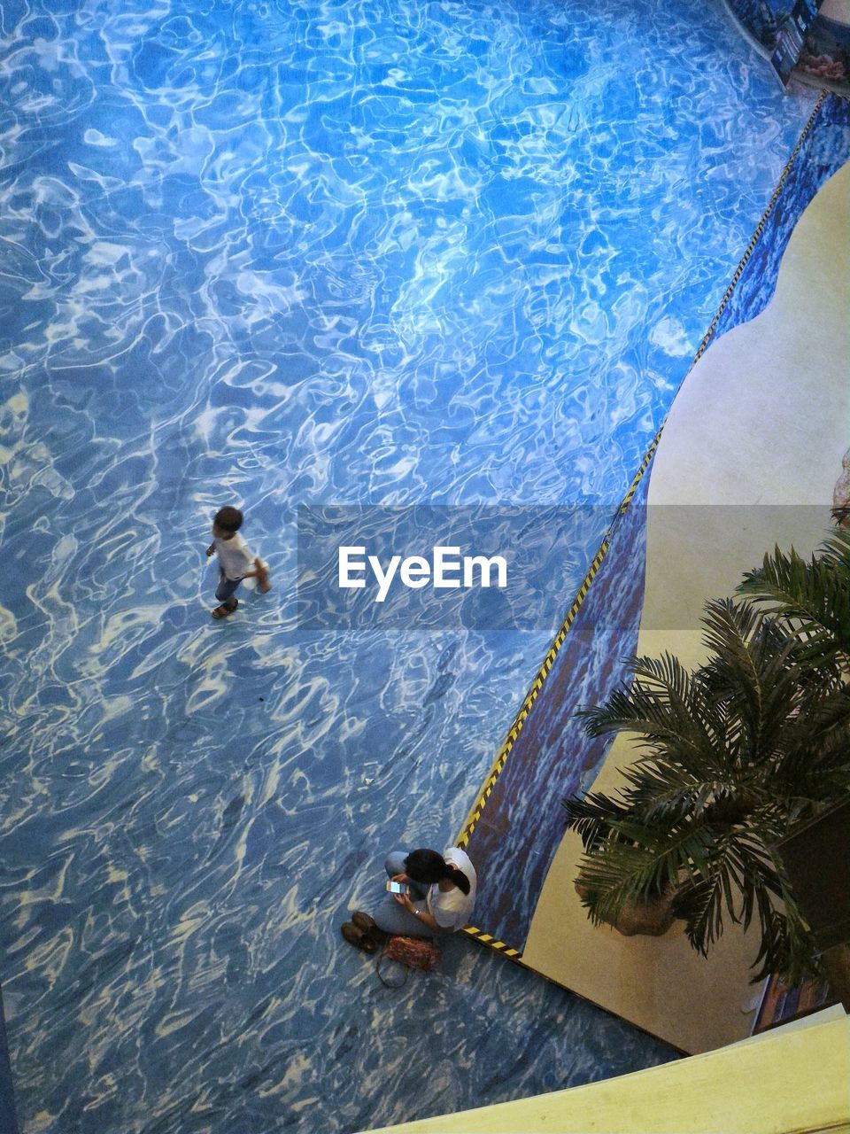 HIGH ANGLE VIEW OF MAN SWIMMING IN SEA