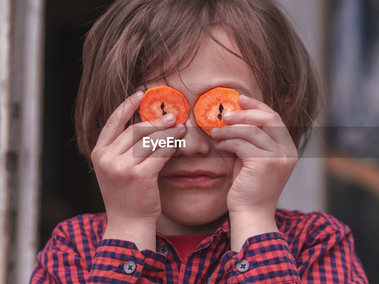 Close-up of girl covering eyes with carrot slices